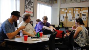 Four Chabot College students gathered around a table discussing the Egypt Station album while they listen to it together.