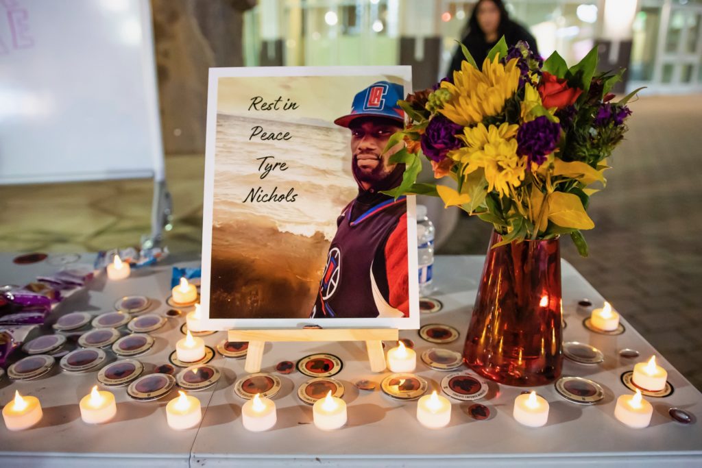 A table and photo dedicated to the memory of Tyre Nichols decorated with candles and buttons.