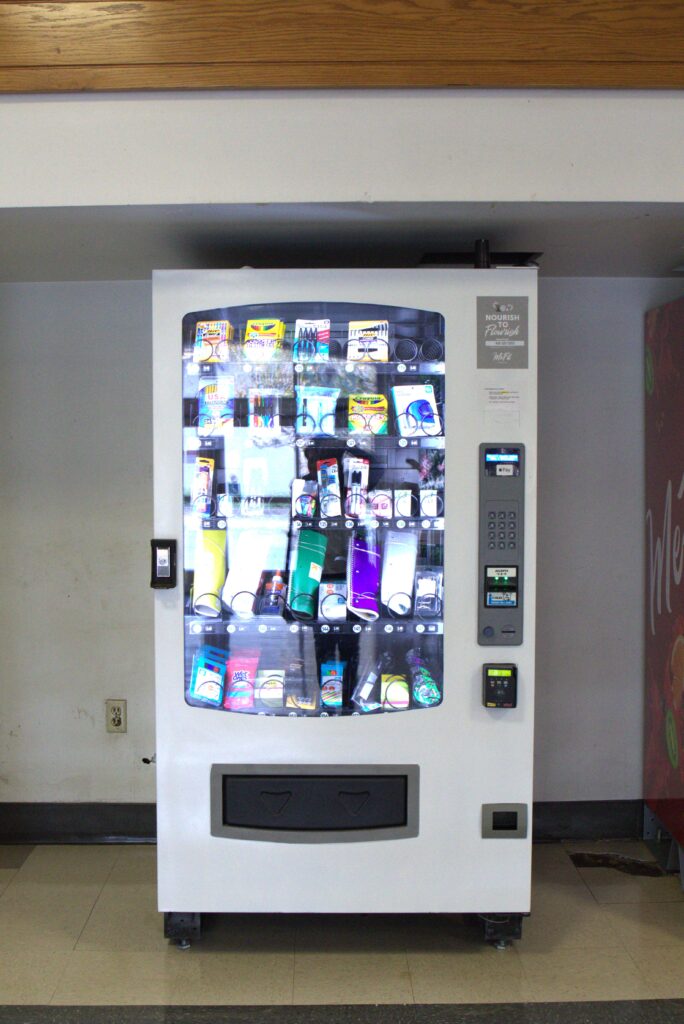 A vending machine filled with various items, including notebooks, pen packs, highlighters, and markers.