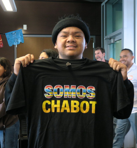 CJ DeGuzman holding a T-Shirt that says "Somos Chabot" after winning hula hoop contest.