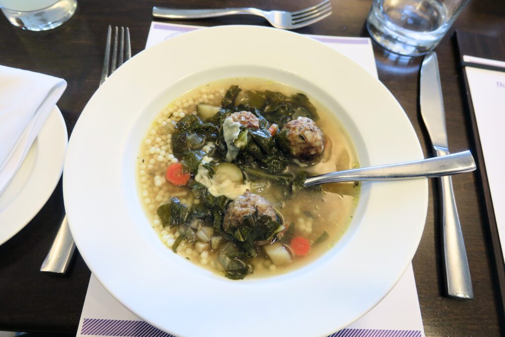 Soup with meatballs, chopped carrots, and spinach. 